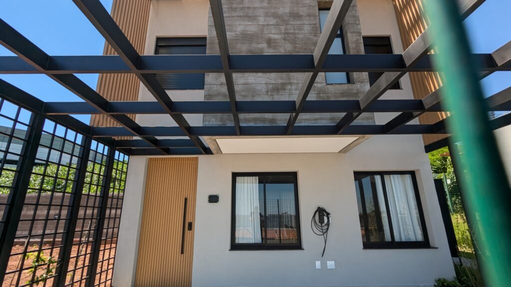 Entrada de uma casa do Oni Dijon com pergolado metálico e ponto preparado para carregador de carro elétrico